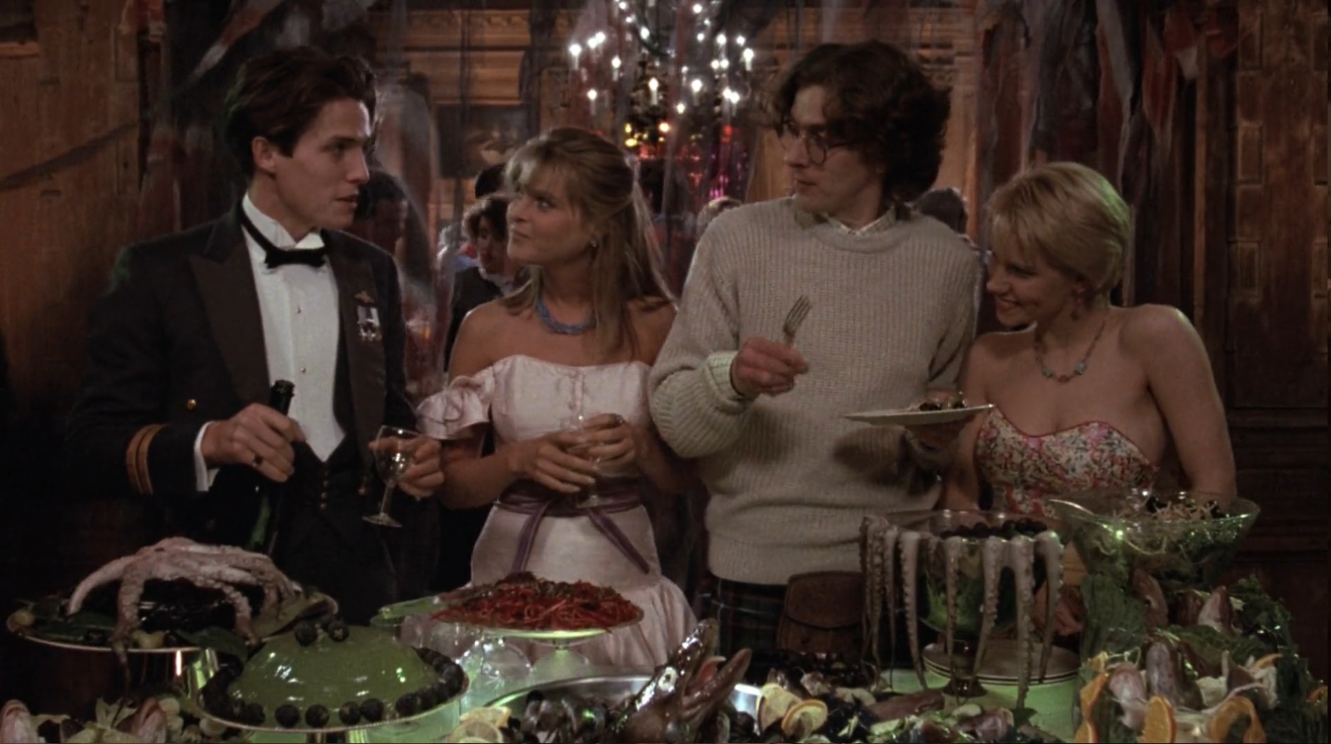 Cena de A Maldição da Serpente mostrando o lorde James D'ampton, Angus Flint, Eve e Mary Trent em frente à uma mesa cheia de comida. Eles estão em um baile pomposo conversando enquanto se servem