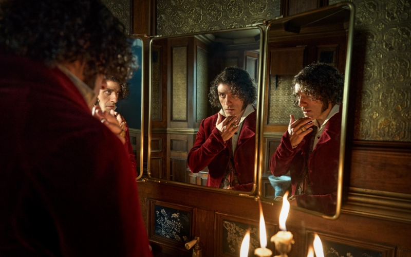 Cena do filme Frankenstein (2025) mostrando Victor Frankenstein olhando-se em um espelho triplo em um banheiro.