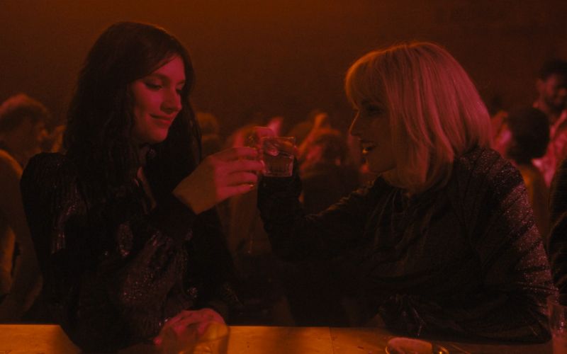 Cena do filme A Primeria Profecia (2024) mostrando Margaret e Luz em uma festa na noite de Roma. Ambas estão maquiadas e tomando shots de bebida alcoólica. Margaret está com seus cabelos soltos e Luz está com uma peruca loira.