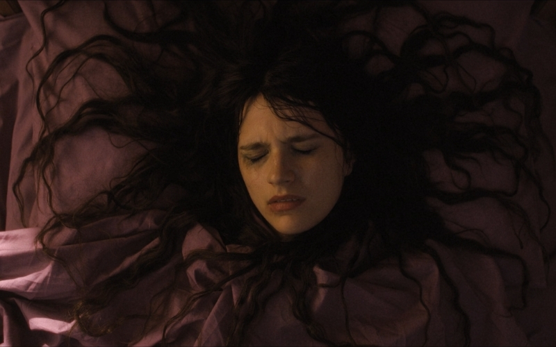 Cena do filme A Primeria Profecia (2024) mostrando Margaret deitada em sua cama com o cobertor (da mesma cor que a cama) tapando-a até o pescoço, passando a impressão que ela é apenas uma cabeça. Seus cabelos estão soltos e espalhados, semelhante às patas de aranhas ou cobras.