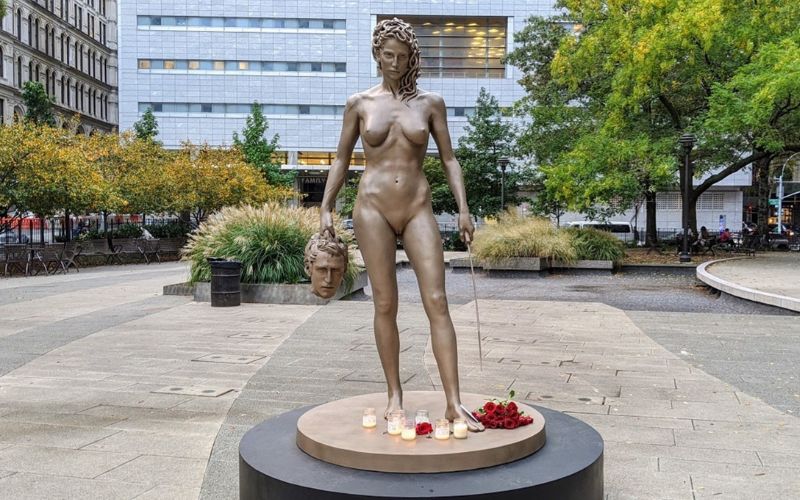 Estátua Medusa segurando a cabeça decaptada de Perseu, esculpida por Luciano Garbati em 2008. Medusa segura na outra mão uma espada. A estátua está posicionada em uma praça ao ar livre, com velas aos seus pés.