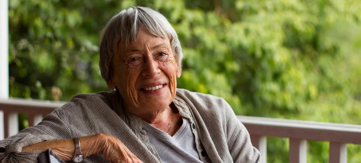 Ursula K. Le Guin sorrindo na varanda de uma casa.