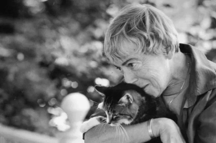Ursula abraçando um gato em uma foto preto e branco.