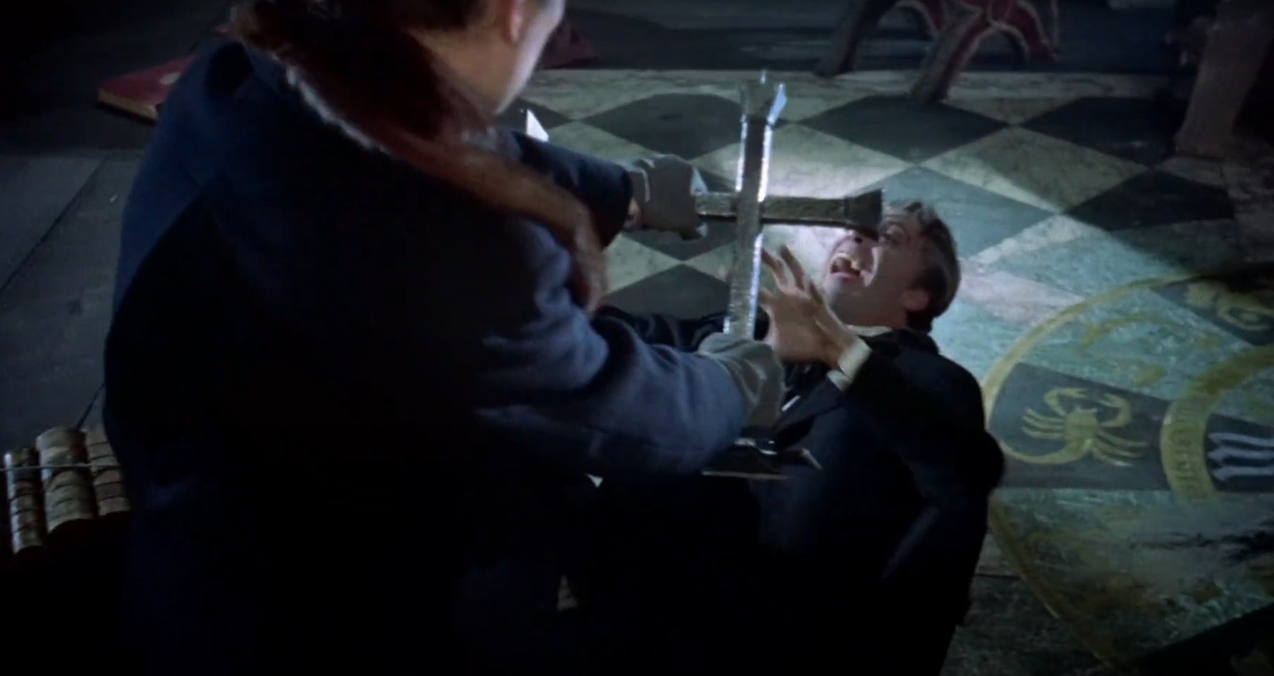 Cena do Filme Drácula de 1958 com o Van Helsing cruzando dois castiçais para formar o símbolo de uma cruz. À sua frente, Drácula agoniza mostrando seus dentes de vampiro.